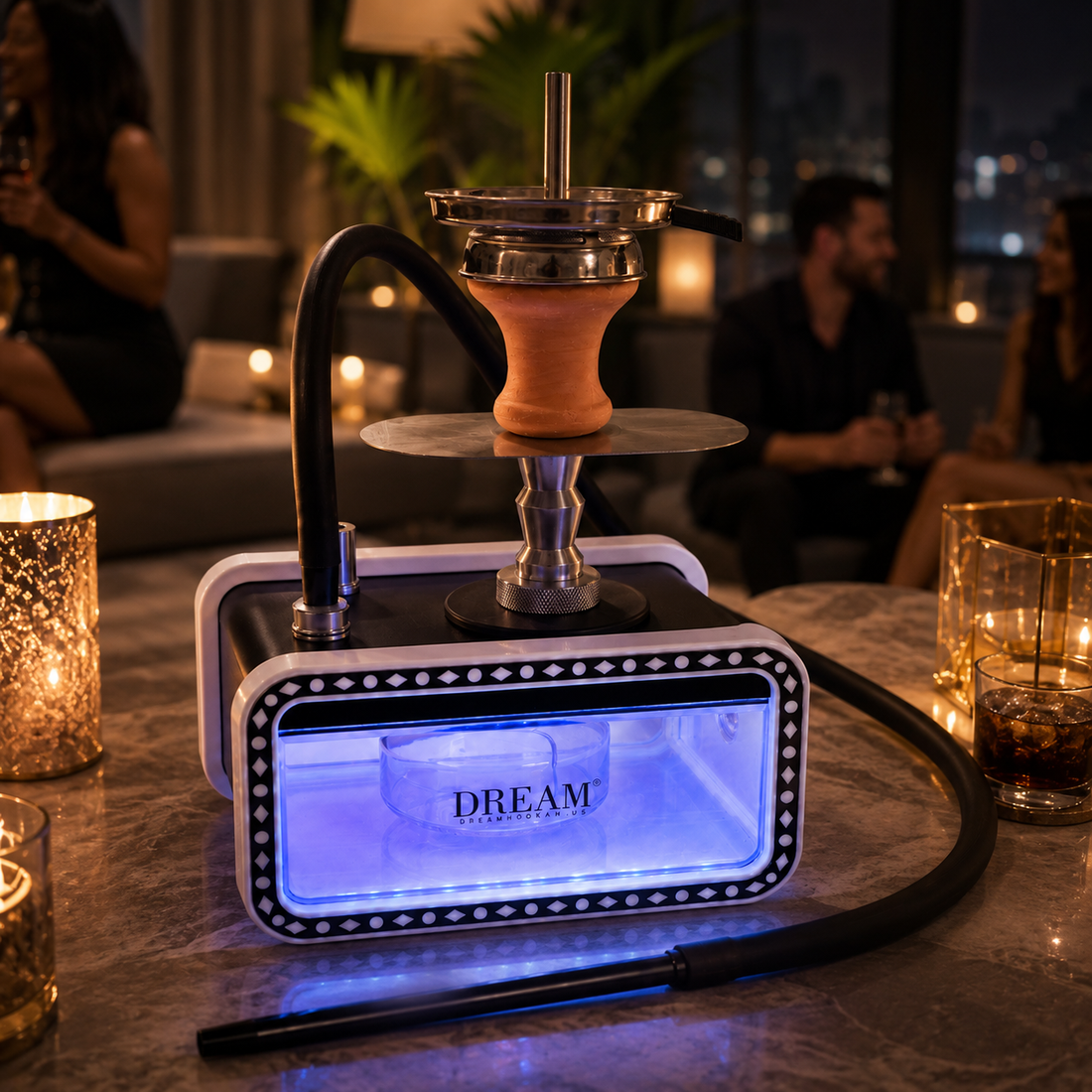 A luxury hookah set on a marble table in a dimly lit, upscale lounge environment. The set features a rectangular base with glowing blue LED lights, a terracotta-colored ceramic bowl, and a black hose.