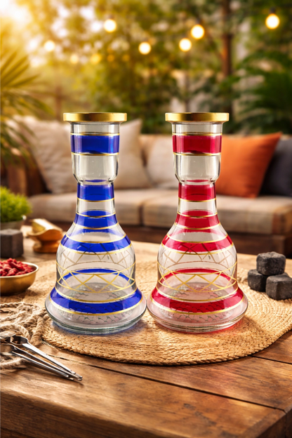 Two glass vases with red and blue stripes on a wooden table outdoors.
