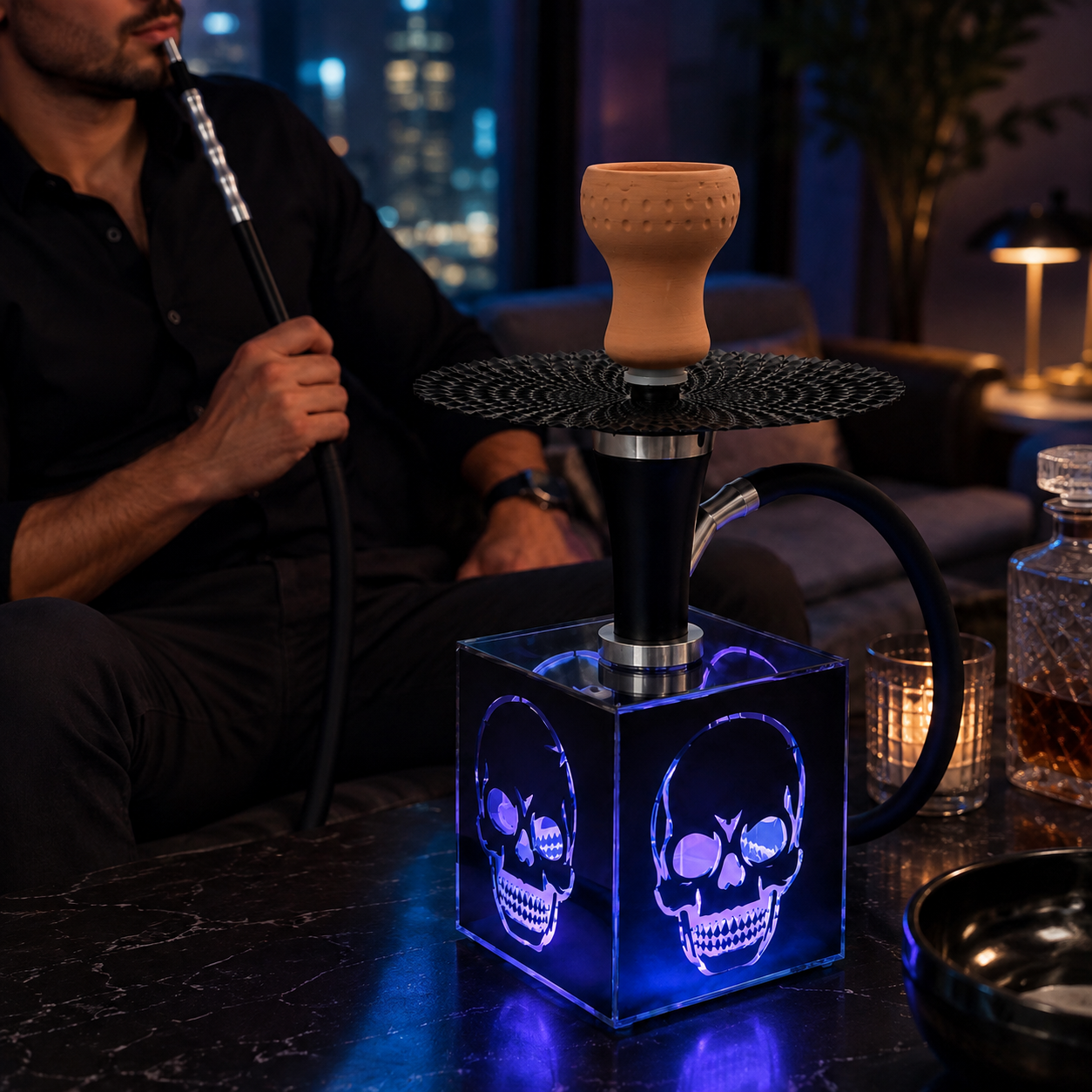 A skull-themed hookah set on a dark marble table in a dimly lit lounge. The hookah has a glowing blue LED cube base with skull designs, a black metal stem, and a beige ceramic bowl.