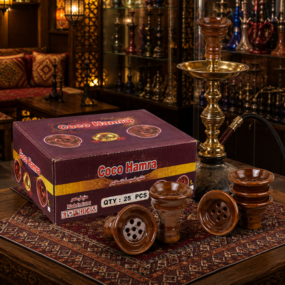A boxed set of Coco Hamra hookah accessories displayed in a warm, ornate shop setting. The set includes a purple and gold box labeled &
